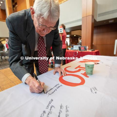 Former Chancellor, Martin Massengale signs one of the four Alumni N150 flags. The flags will travel around the world to various alumni chapters and be signed. They will return in the fall and be hung for homecoming weekend for all to see. Everyone was invited to enjoy a cupcake and join in the festivities with their Husker friends at the Wick Alumni Center, Friday February 15th. The Nebraska Charter was available to view, along with other historical items. Copies of Dear Old Nebraska U could be purchased and signed. Charter Day at the Wick Alumni. February 15th, 2019. Photo by Gregory Nathan / University Communication.